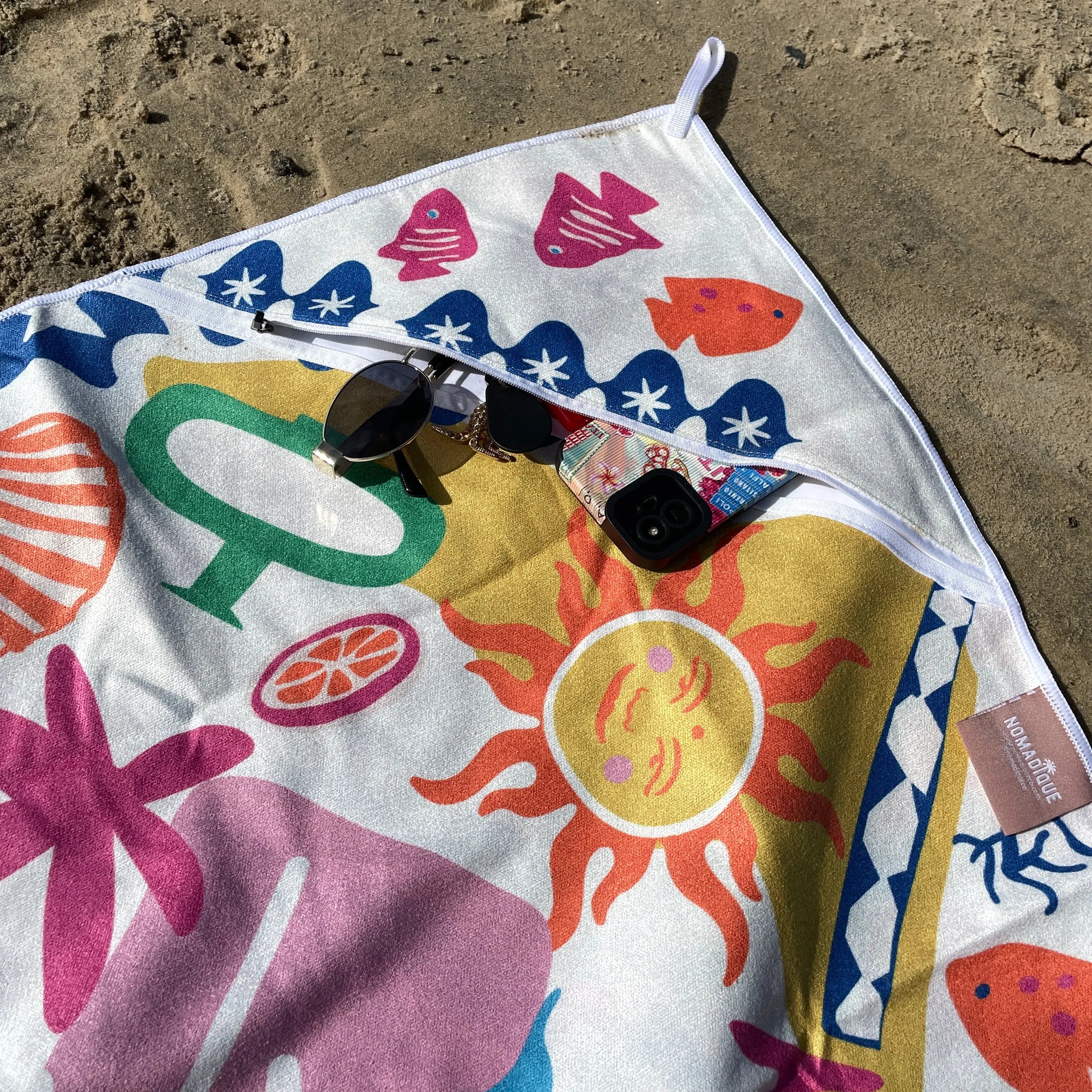 Bright shades of turquoise, pink, orange, yellow, and white are arranged in a playful, summery pattern that stands out sharply against the neutral sand.